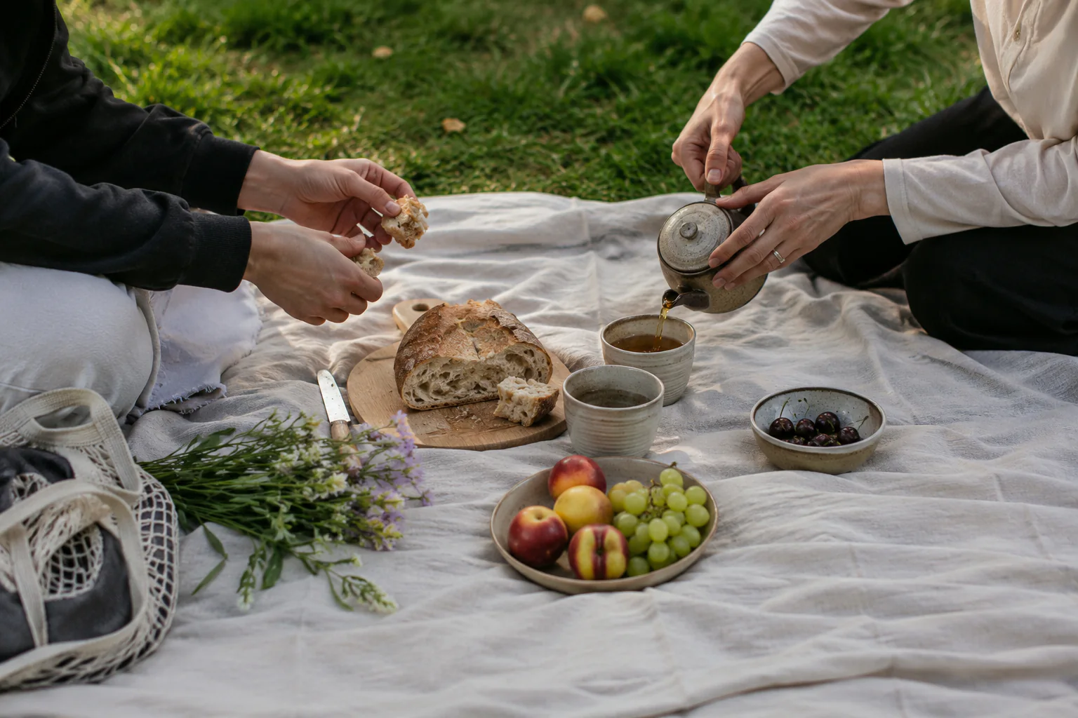 Zwei Menschen teilen bei einem Picknick Brot und Tee
