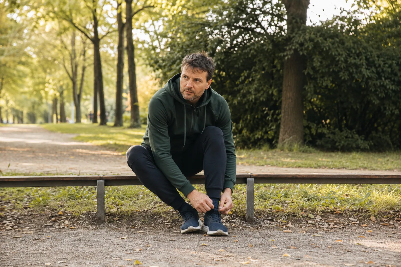 Ein Mann bindet auf einer Parkbank seine Laufschuhe